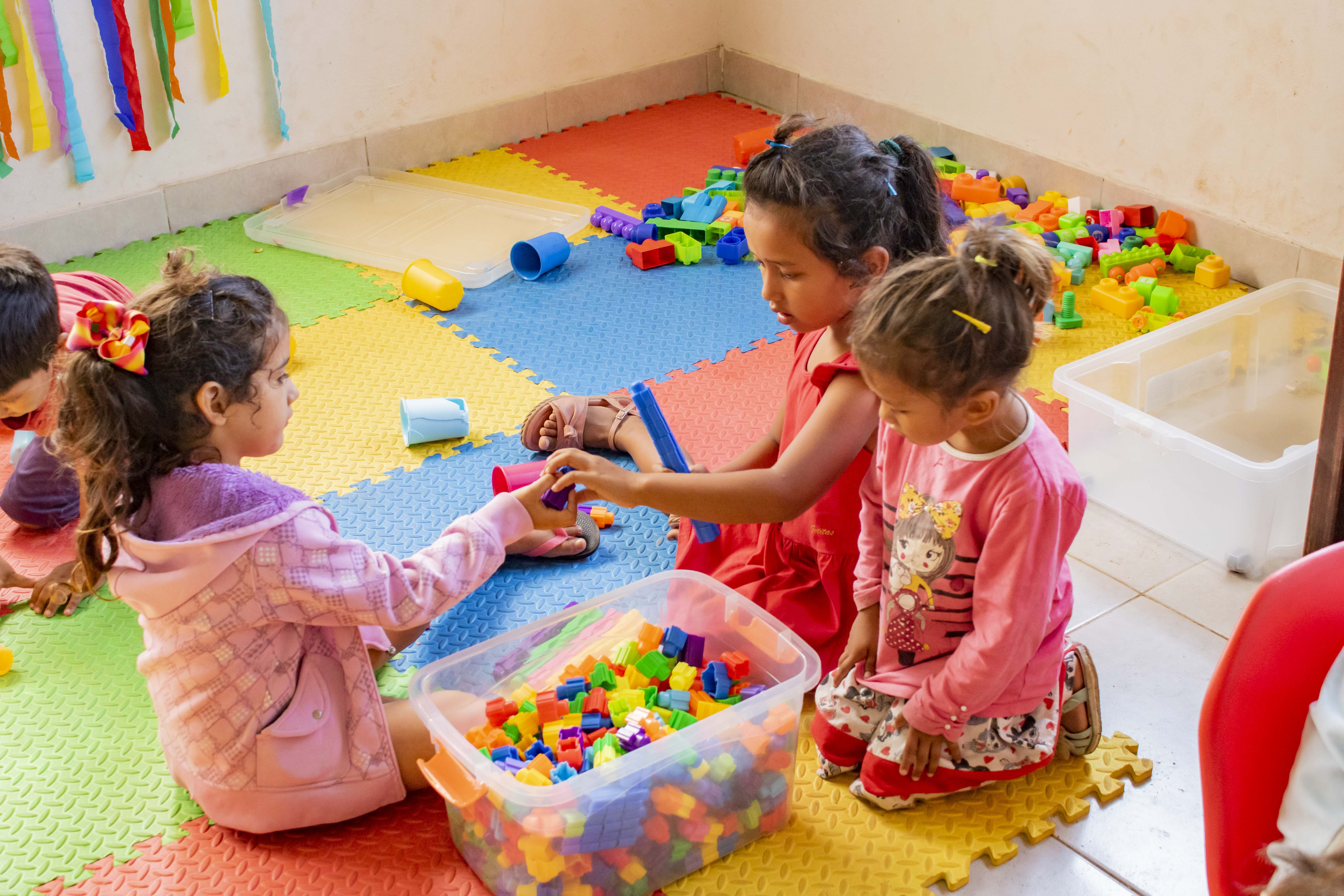 niñxs jugando en el piso, con piezas de construcción.